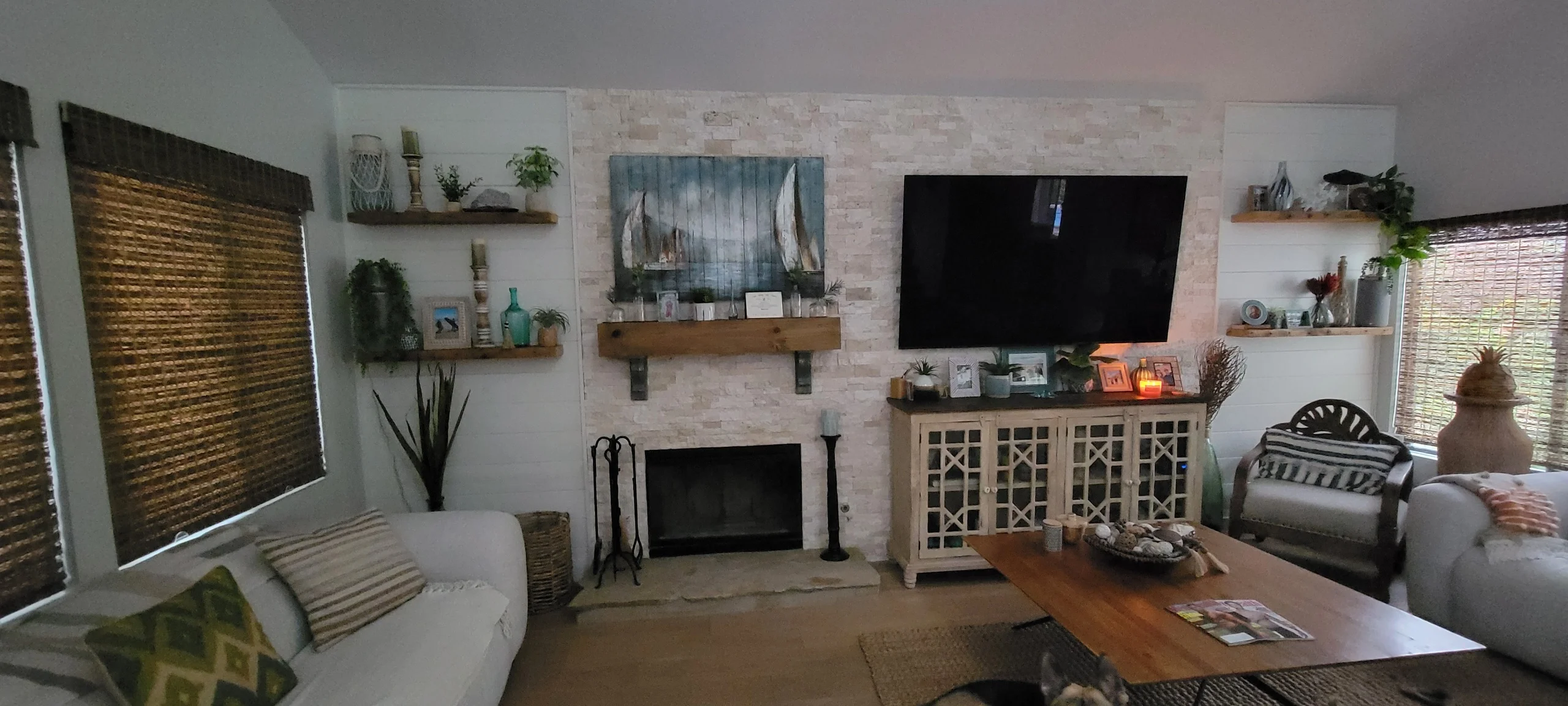 Stacked stone fireplace with floating shelves, built-in cabinetry, and mounted TV in modern living room