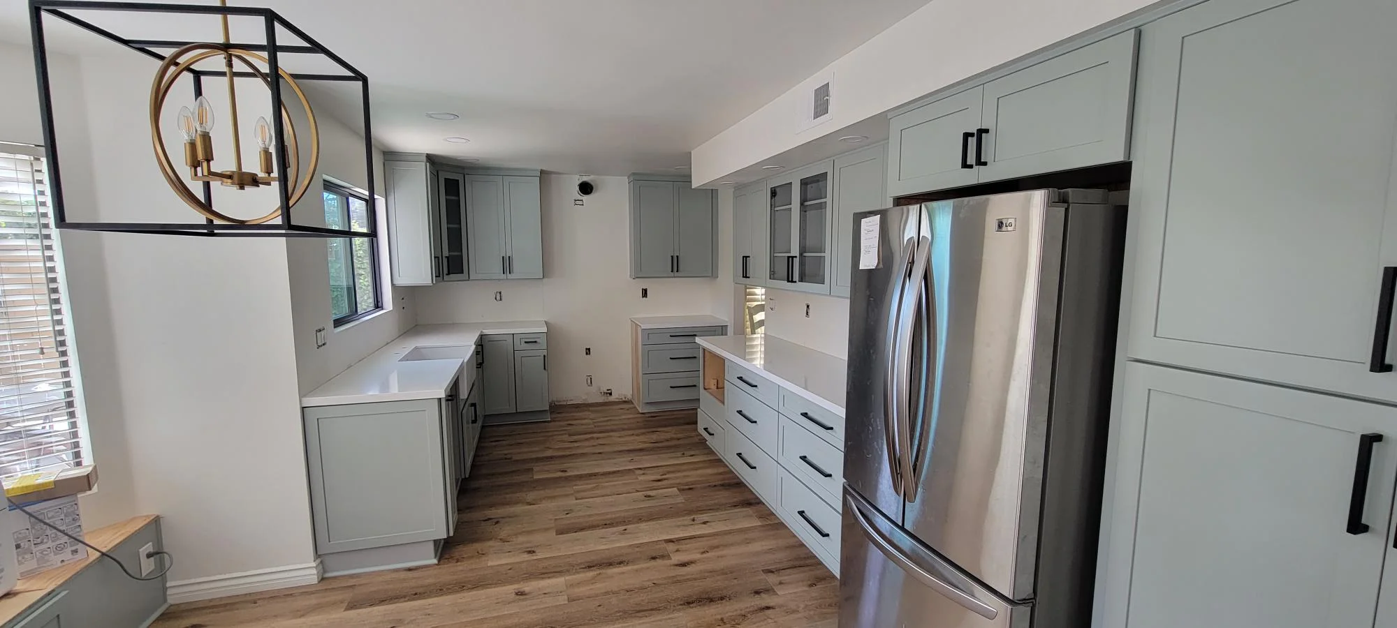 Modern kitchen with gray cabinetry, white counters, stainless appliances, and wood flooring