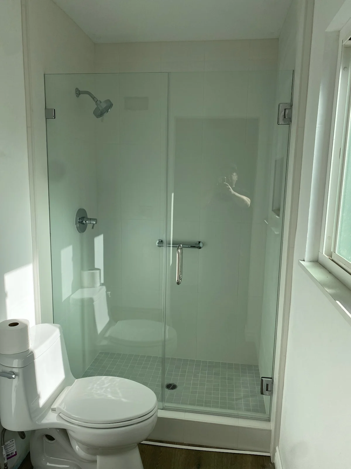 Frameless glass shower enclosure with chrome fixtures and small-format tile floor