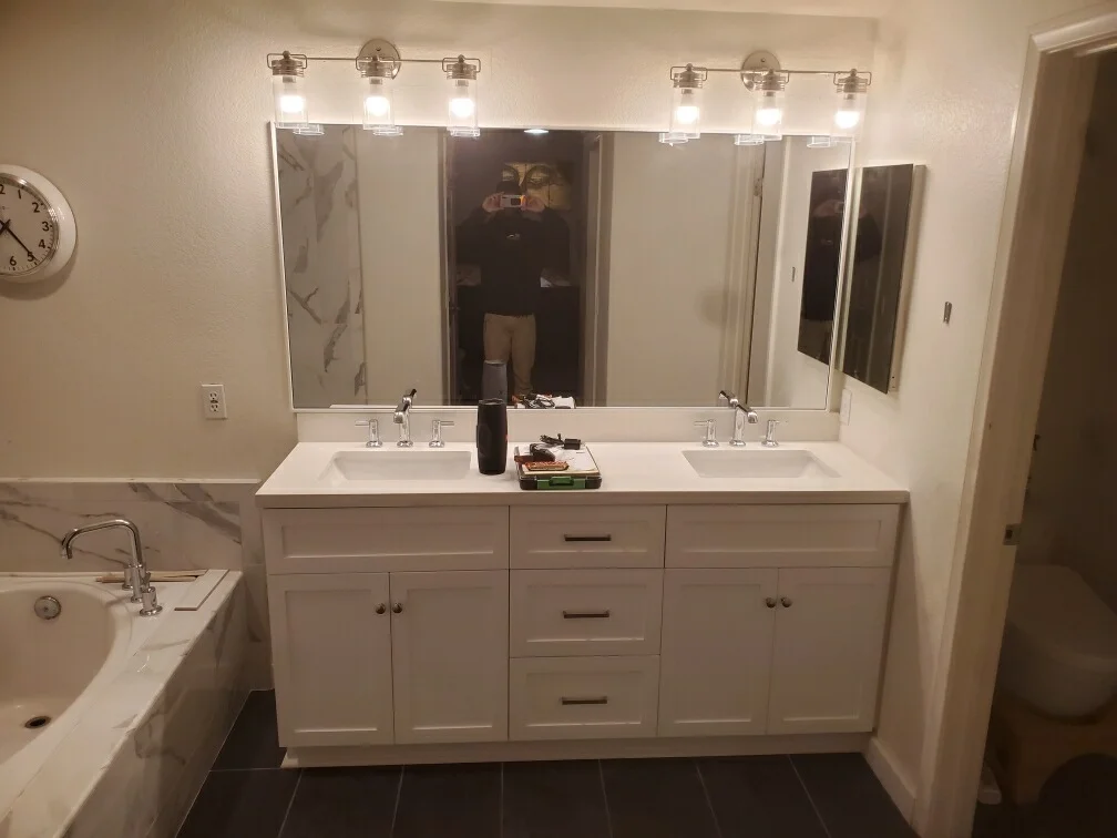 Dual sink vanity with white cabinetry, quartz countertop, framed mirrors, and vanity lighting
