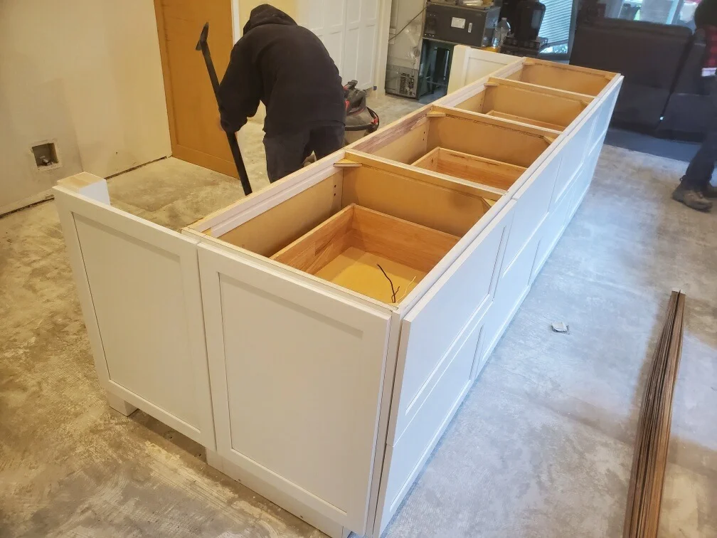 White kitchen cabinets with open compartments during installation, shaker-style doors