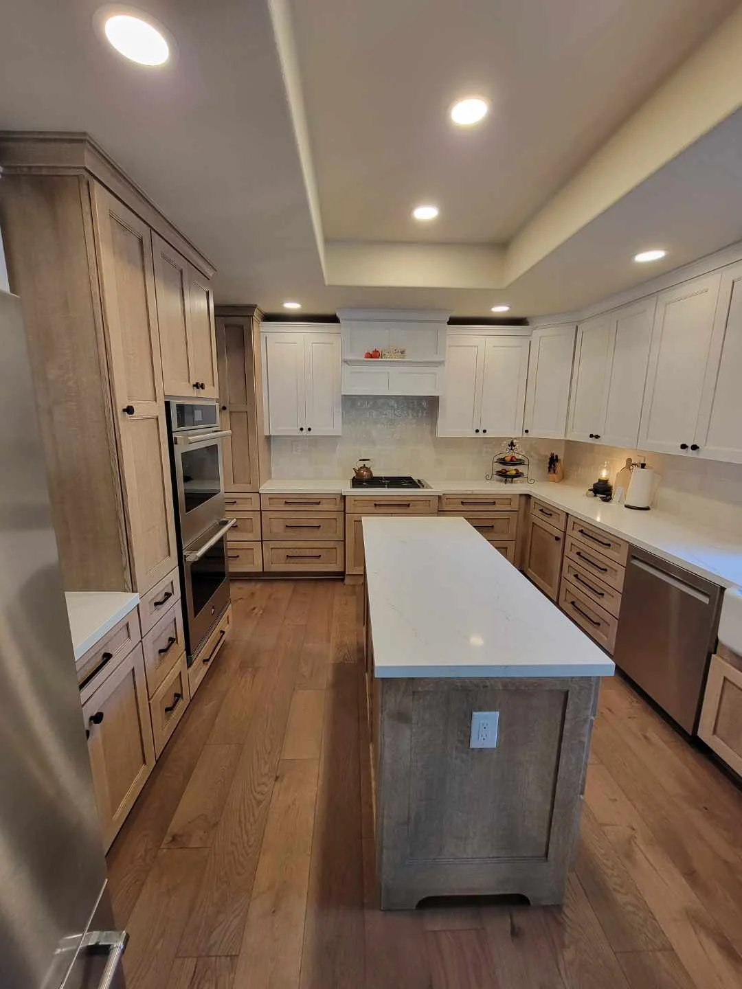 Kitchen with custom wood and white cabinetry, quartz countertops, center island, hardwood floors, and recessed lighting