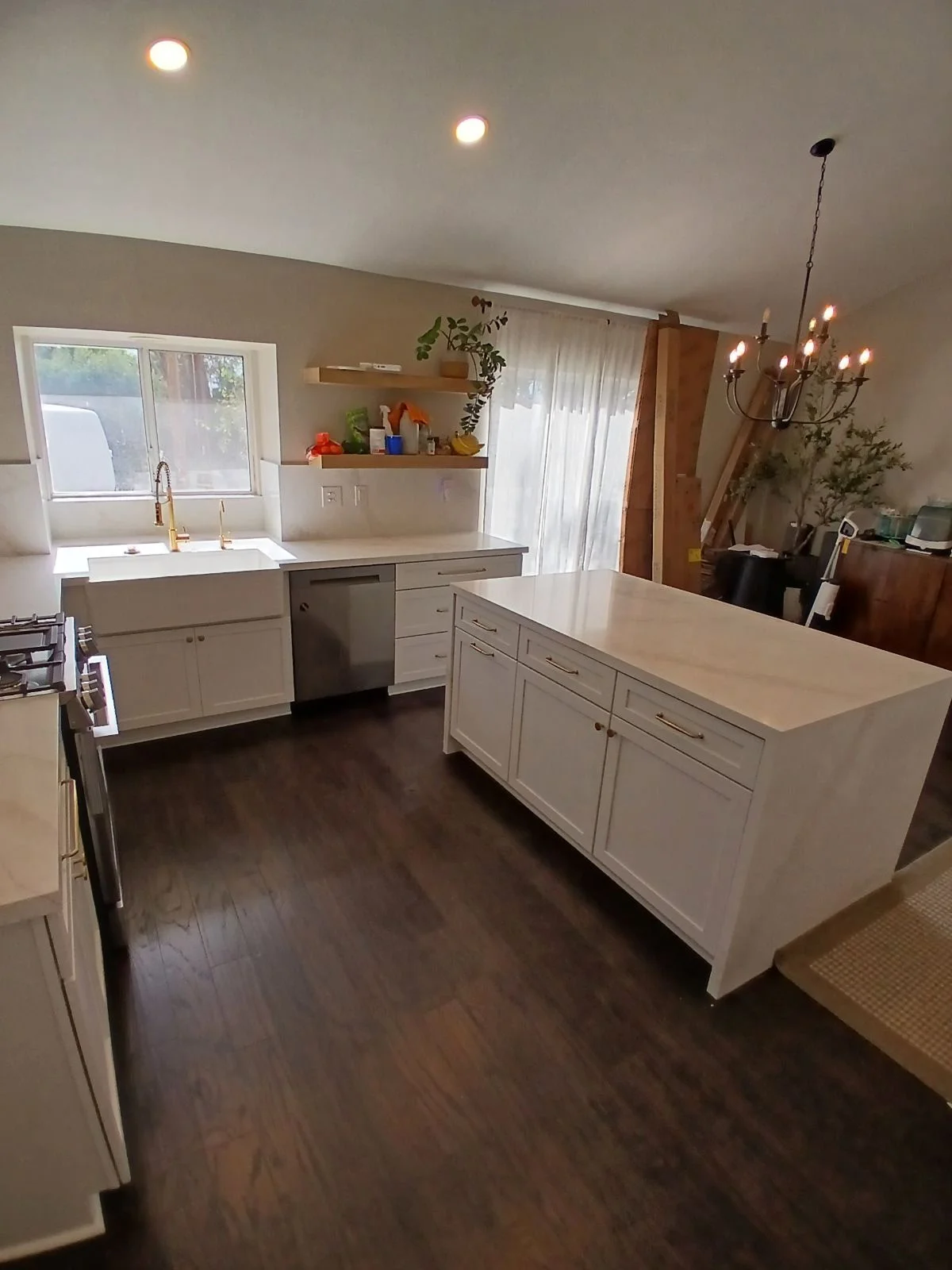 White kitchen cabinets, quartz countertops, island, stainless steel appliances, hardwood flooring