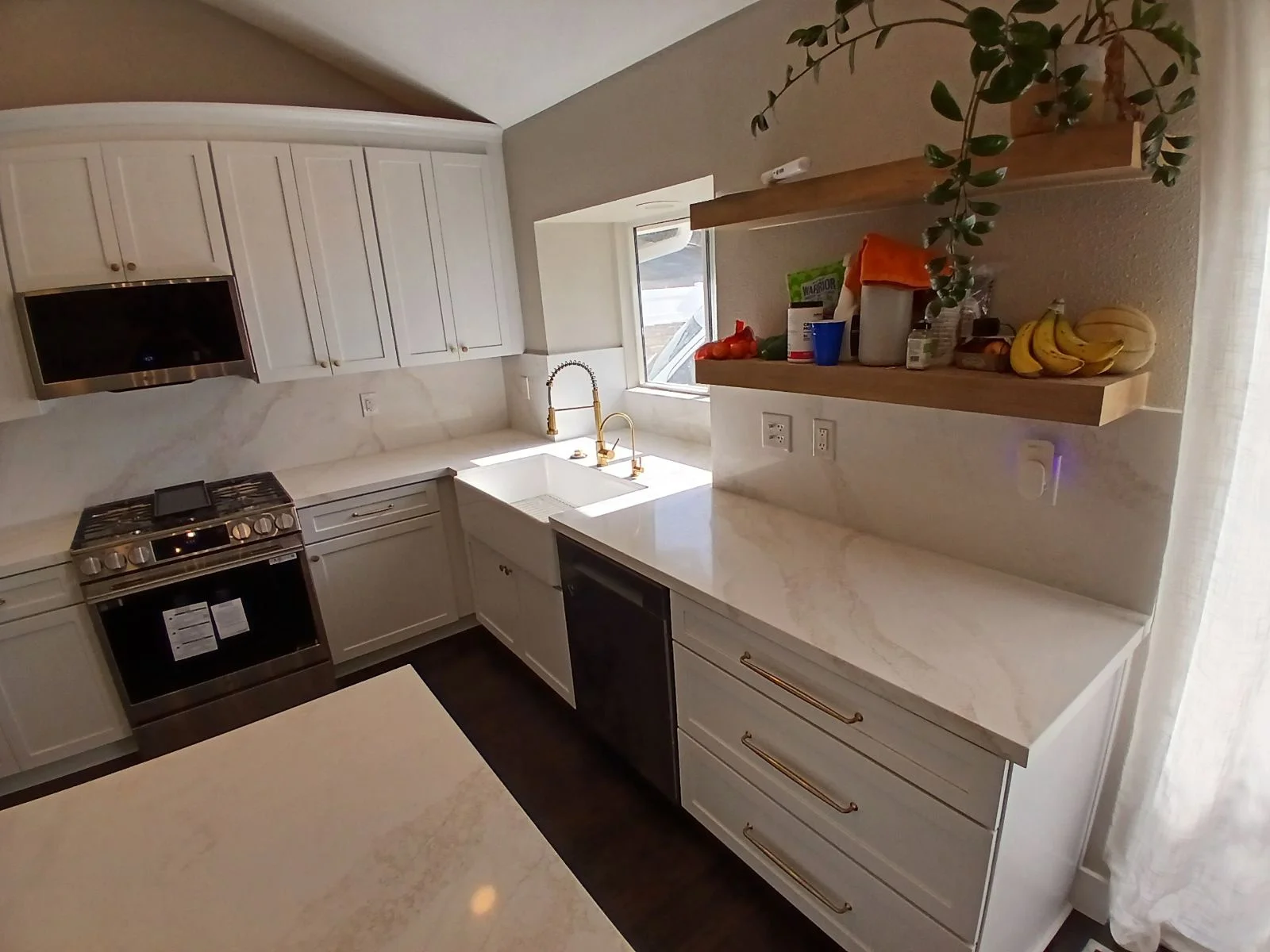 White kitchen with quartz counters, stainless steel range, floating wood shelves, and subway tile backsplash