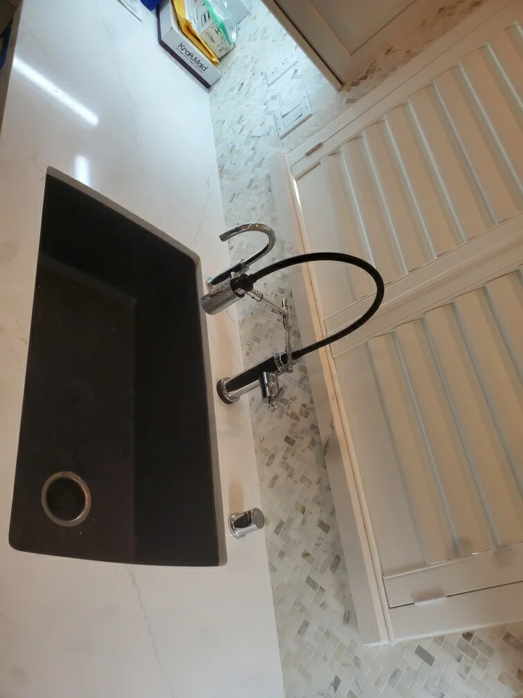 Dark vessel sink with chrome faucet and marble mosaic tile backsplash in renovated bathroom