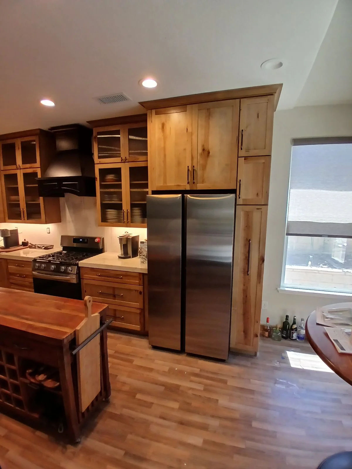Kitchen with knotty alder cabinetry, stainless steel appliances, quartz counters, and hardwood flooring