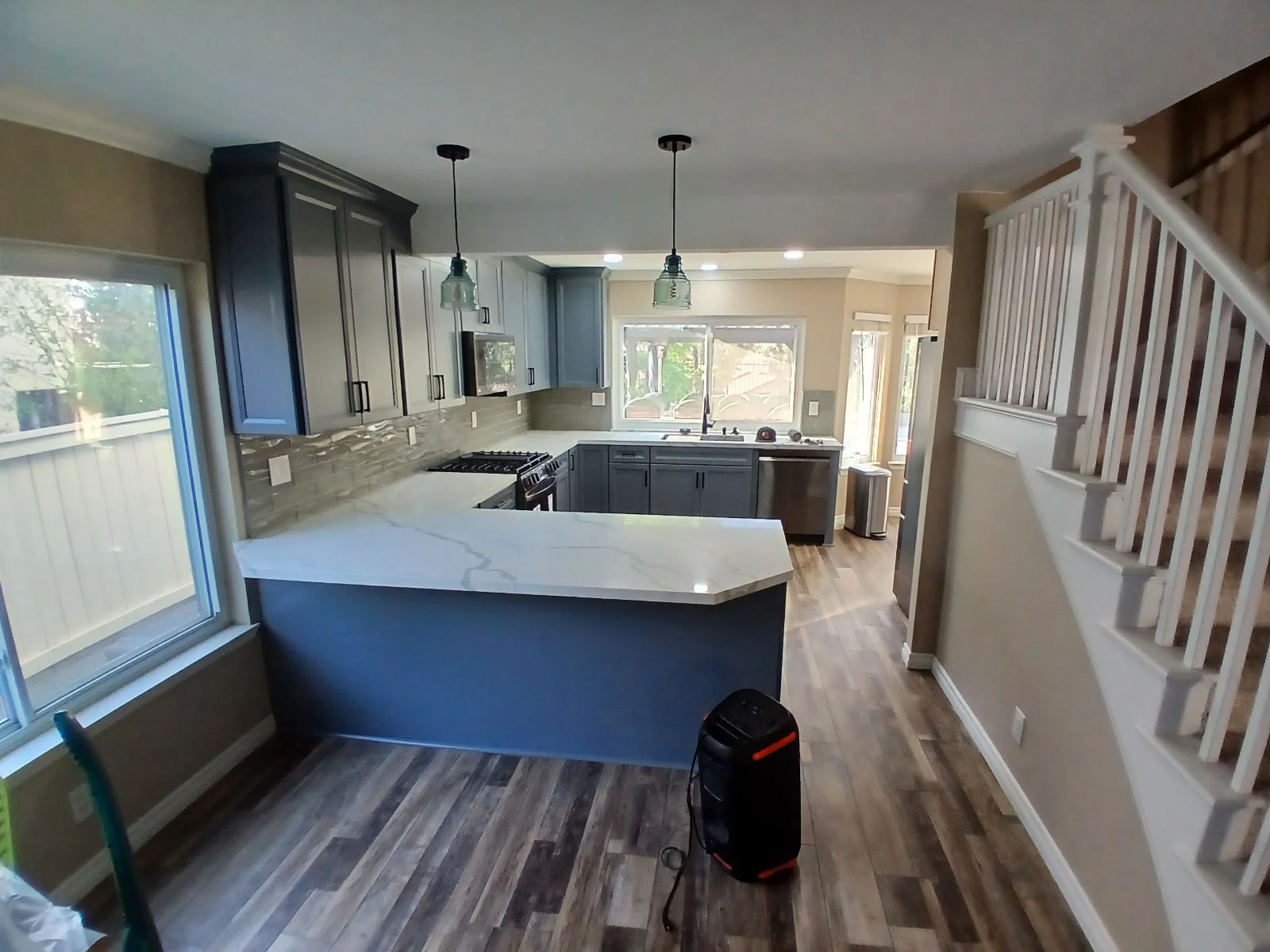 Modern kitchen with dark cabinets, white quartz counters, island, stainless appliances, and vinyl plank flooring