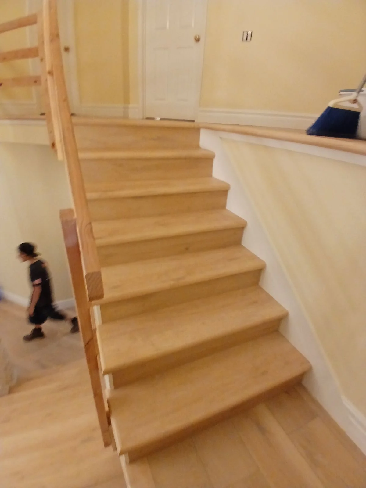 Wooden staircase with natural finish treads, white walls, and wooden railings in residential interior