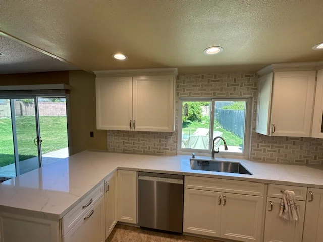 Kitchen with cream cabinets, quartz counters, brick tile backsplash, and stainless steel sink