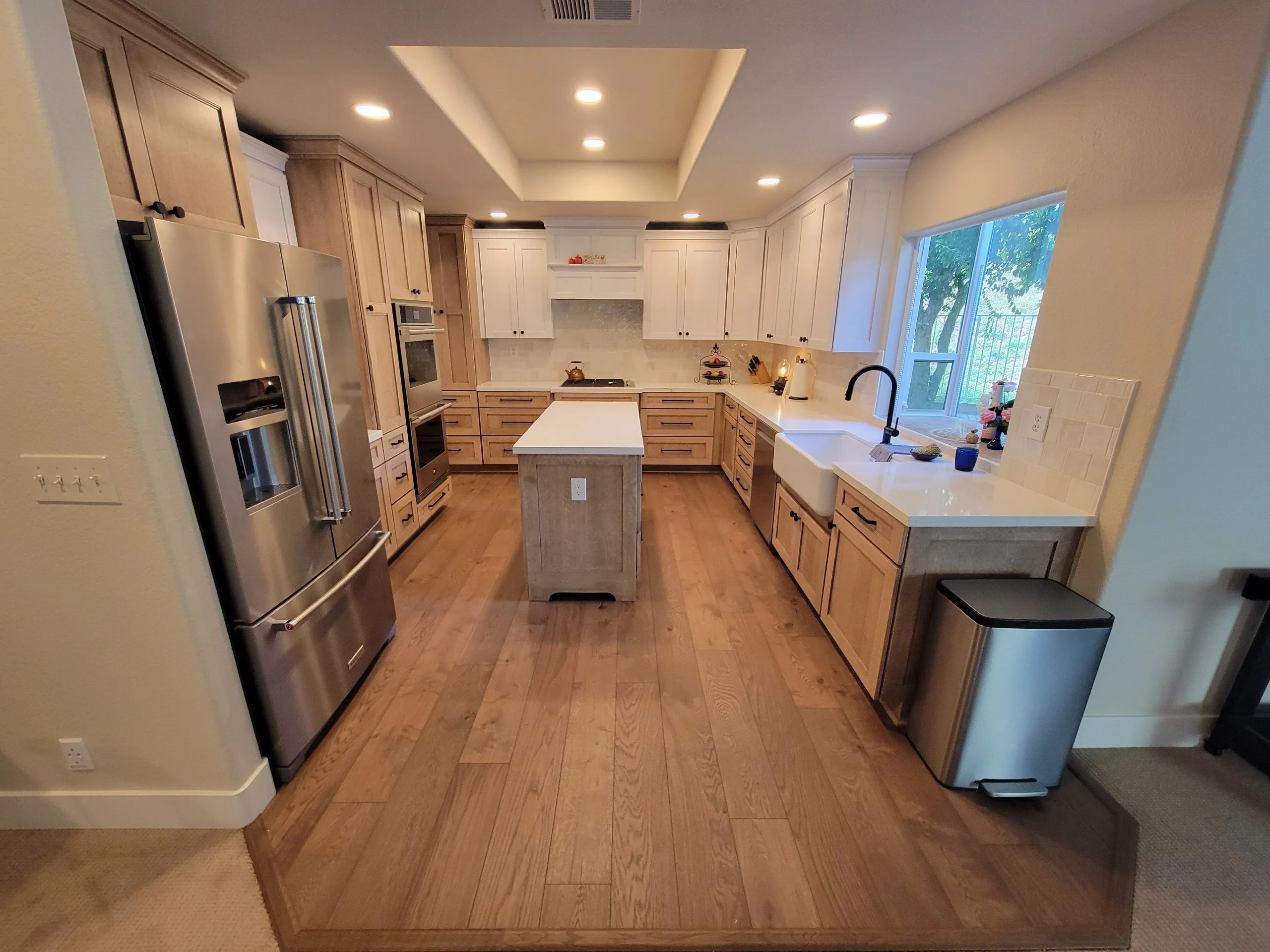 Kitchen with wood cabinetry, quartz counters, stainless steel appliances, hardwood floors, and island