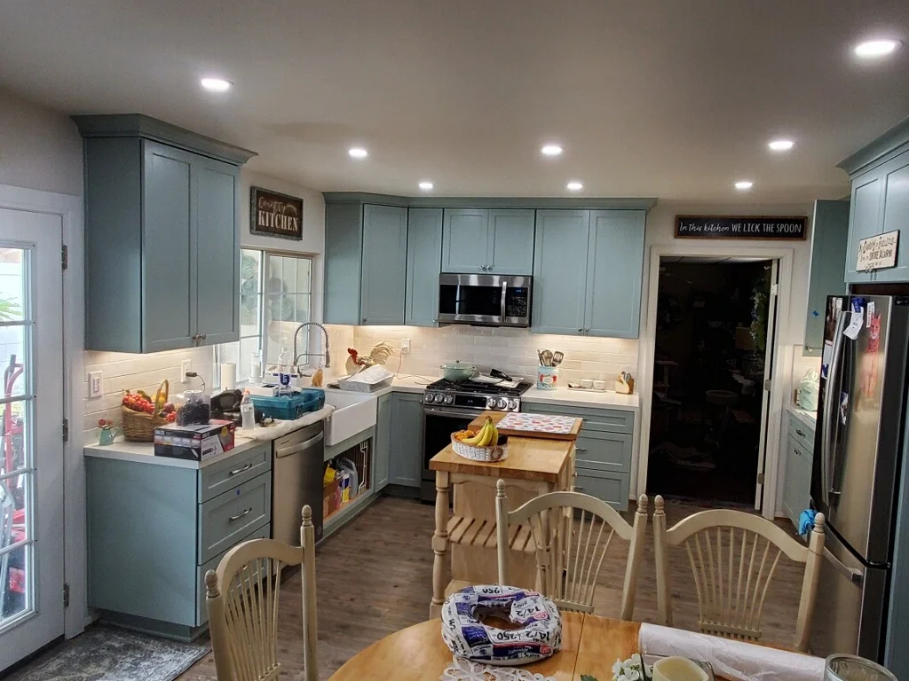 Kitchen with blue-gray cabinets, white subway backsplash, black range, and wood island