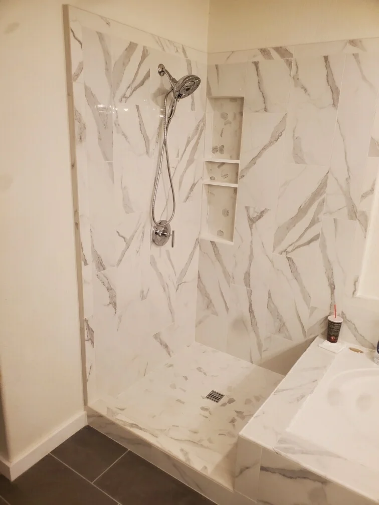 White marble tile shower with chrome fixtures and recessed niche shelving